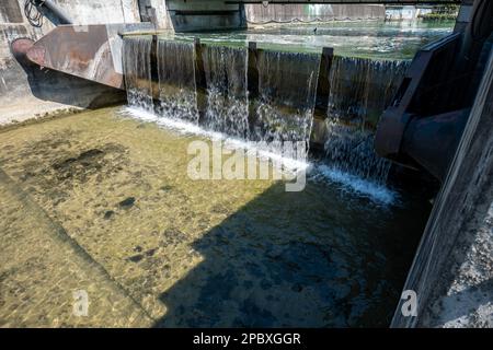 River water pouring down from dam flood gates of a water treatment plant in Europe. Summer day, no people. Stock Photo