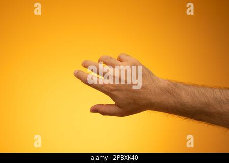 Open Caucasian male hand. Close up studio shot, isolated on orange background. Stock Photo