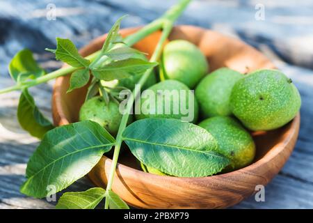 Killograms of green non-ripe walnuts are cooked before ripening for preparation of medicinal tincture or drug. branch of walnut with young leaves on s Stock Photo