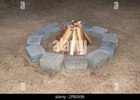 Prepared chopped pieces of wood to make a fire in a stone circle on the sand. Stock Photo