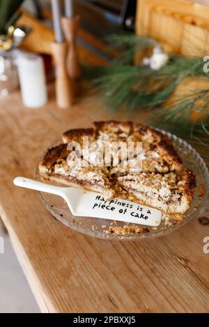 Sweet homemade pie with words of encouragement : Happieness is a piece of cake, painted on spatula. motivational message held. rustic background. Stock Photo