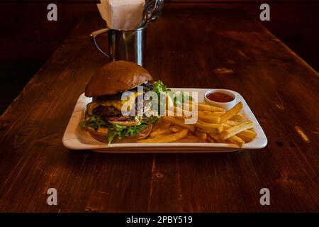 Homemade cheeseburger with cheese and vegetables served with french fries and salad Stock Photo