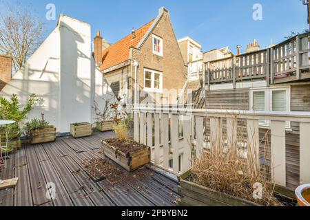 Exterior of old typical residential building with windows and fence near house plants under blue sky Stock Photo