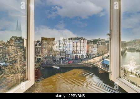 View through opened window on aged typical city buildings and bridge over river on sunny day Stock Photo