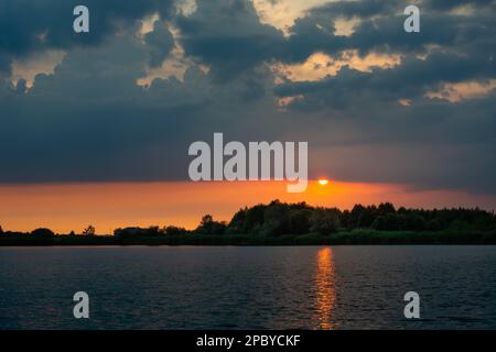 Sunset with dark clouds over the calm lake Stock Photo