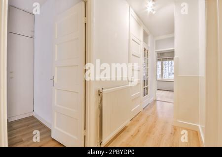 Interior design of empty long hallway with white walls and wooden floor with doors illuminated by ceiling lamps in modern house Stock Photo