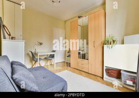 Contemporary interior design of living room furnished with comfortable couch and wooden wardrobe with table and chairs decorated with green plants Stock Photo