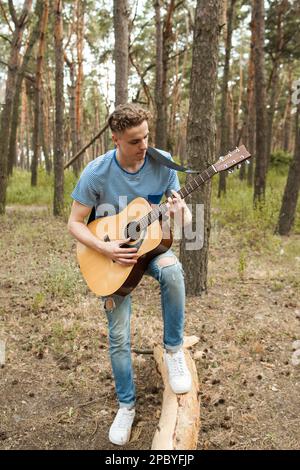 Pensive man playing guitar forest concept. Stock Photo
