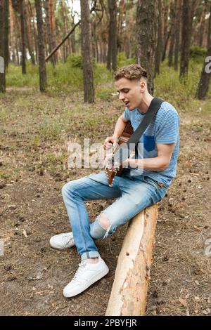 Handsome man song playing guitar forest concept. Stock Photo