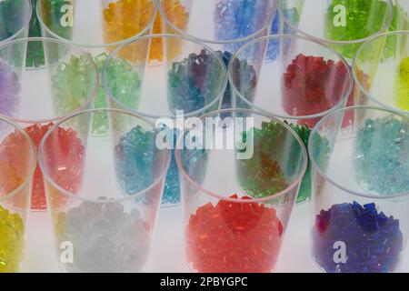 several transparent colored plastic resin granulates in test glasses in laboratory. Mass for injection molding and extrusion process Stock Photo