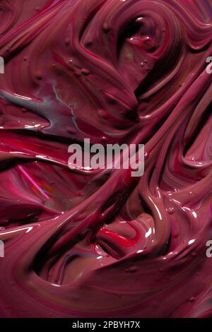 Closeup shot of swirls on surface of thick paint mixing to dark red color Stock Photo