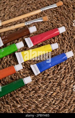 photo lots of paints in tubes and paint brushes on a wicker napkin Stock Photo