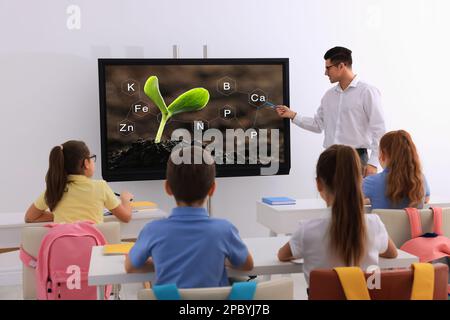 Teacher using interactive board in classroom during lesson Stock Photo
