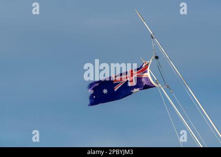 A torn and shredded Australian national flag (blue ensign) hanging from a boat mast on the Central Coast of New South Wales, AUSTRALIA Stock Photo