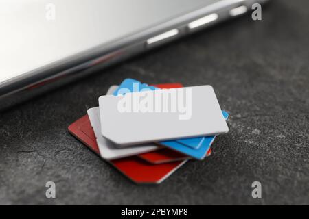 SIM cards and mobile phone on grey table, closeup Stock Photo