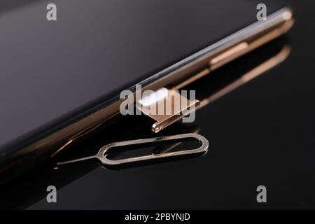 SIM card, smartphone and ejector on black background, closeup Stock Photo