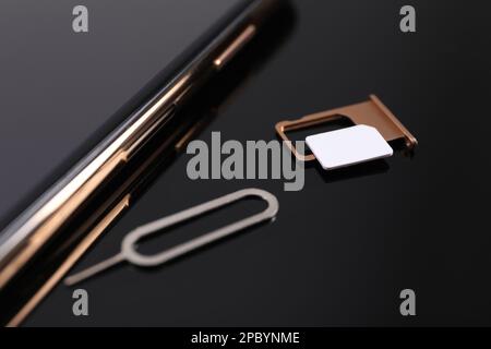 SIM card, smartphone and ejector on black background, closeup Stock Photo