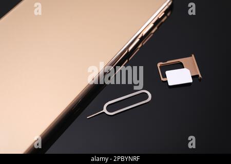 SIM card, smartphone and ejector on black background, above view Stock Photo