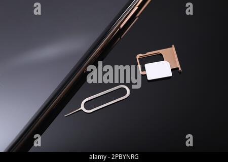 SIM card, smartphone and ejector on black background, above view Stock Photo