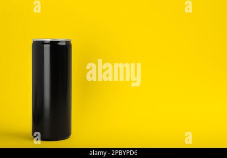 Black can of energy drink on yellow background. Space for text Stock Photo