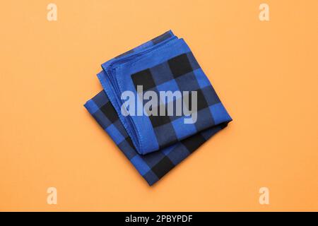 Folded blue checkered bandana on orange background, top view Stock Photo