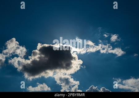 Dramatic puffy white clouds in the blue sky, sun cover behind the clouds, summed day, no people.. Stock Photo