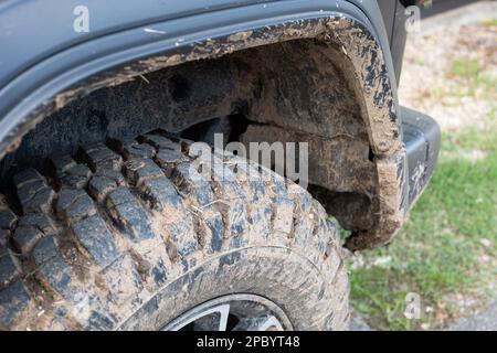 Dried mud on SUV's off-road mud tires. Close up low angle view, no people. Stock Photo