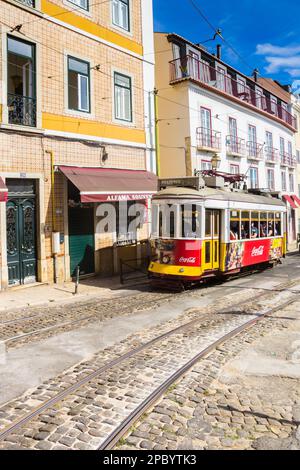 Traditional red and yellow tram in a cobblestoned street of Lisbon, Portugal Stock Photo