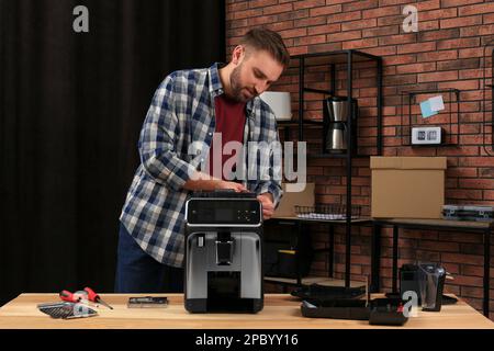 Man fixing coffee machine at table indoors Stock Photo
