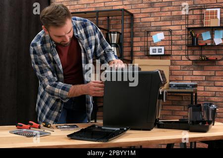 Man fixing coffee machine at table indoors Stock Photo