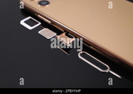 SIM card, smartphone and ejector on black background, closeup Stock Photo