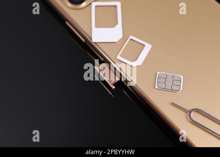 SIM card, smartphone and ejector on black background, closeup Stock Photo