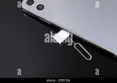 SIM card, smartphone and ejector on black background, above view Stock Photo