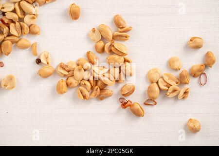 Spicy flavored peanut kernel spilling on white table background. Stock Photo