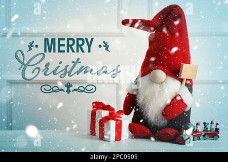 Merry Christmas! Cute gnome, gift boxes and toy train on white wooden table Stock Photo