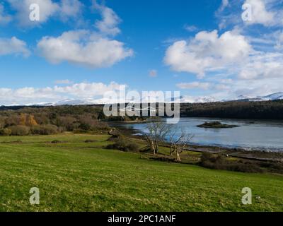 View across Menai Strait to Menai Bridge and Church Island  with snow covered Carneddau Mountains in the background on bright sunny winter's day Stock Photo