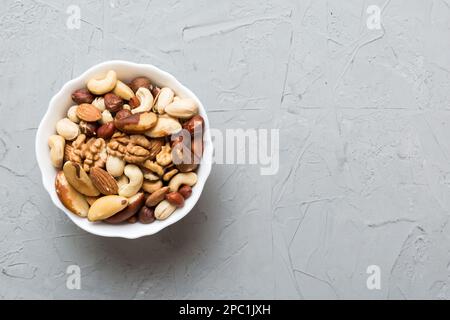 mixed nuts in bowl. Mix of various nuts on colored background. pistachios, cashews, walnuts, hazelnuts, peanuts and brazil nuts. Stock Photo