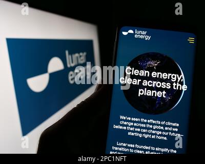 Person holding smartphone with webpage of US company Lunar Energy Inc. on screen in front of business logo. Focus on center of phone display. Stock Photo