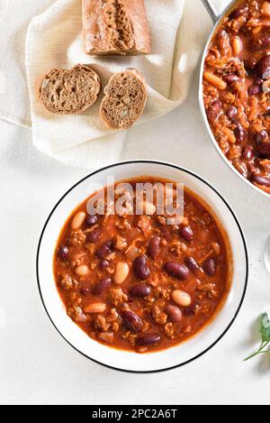 Cowboy beans with ground beef, jalapeno pepper and bacon in bowl over light stone background. Top view, flat lay Stock Photo