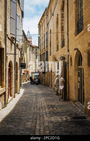 Quaint shops and facades on the cobblestone paved street of Rue de la foire in the old medieval town of Pezenas in the south of France (Herault). Stock Photo