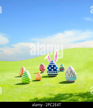 Easter eggs with bunny ears on green grass mountain and blue sky background, happy easter celebration concept Stock Photo