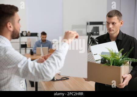 Boss with paper sheet dismissing man from work in office Stock Photo