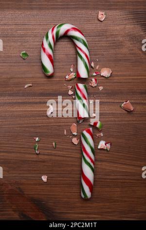 Broken sweet Christmas candy cane on wooden table, top view Stock Photo