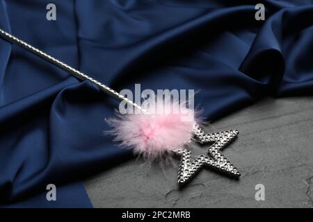 Beautiful silver magic wand with feather and blue fabric on black table Stock Photo