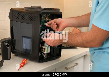 Man fixing coffee machine at table indoors, closeup Stock Photo