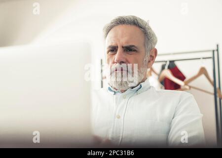 Grey-haired bearded male entrepreneur working on his laptop. A focused middle-aged man. High quality photo Stock Photo