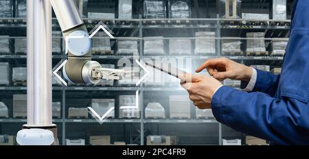 Warehouse manager with digital tablet controls robot arm Stock Photo