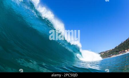 Wave hollow crashing breaking blue water tube close-up swimming encounter towards shallow reefs a scenic beach coastline. Stock Photo