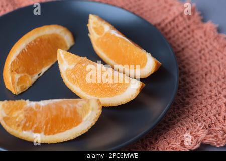 Orange slices on black plate, closeup. Selective focus. Stock Photo