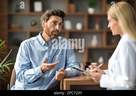 Male Patient Sharing Health Problems With Doctor Woman During Meeting In Office Stock Photo